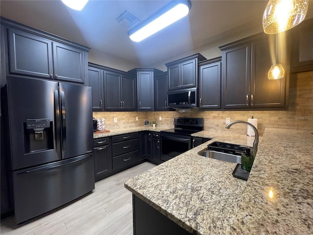 kitchen featuring sink, decorative backsplash, light stone countertops, decorative light fixtures, and stainless steel appliances