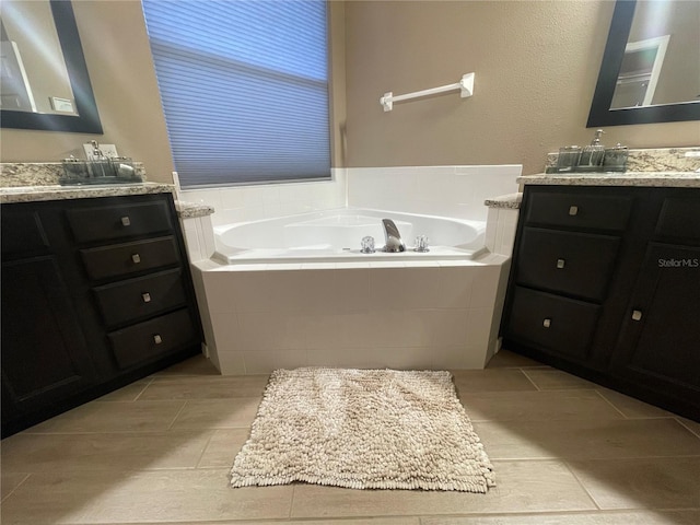 bathroom featuring tile patterned flooring, vanity, and a relaxing tiled tub