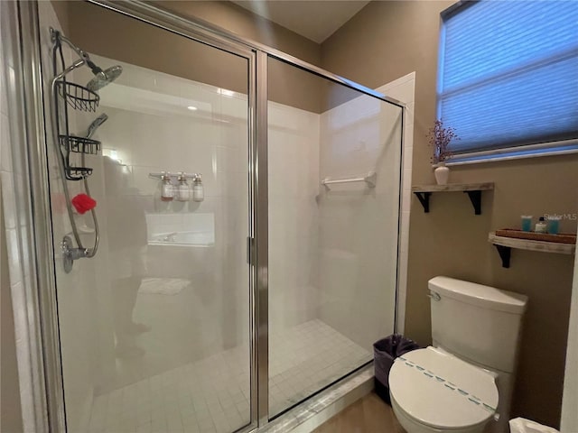 bathroom featuring toilet and a shower with shower door