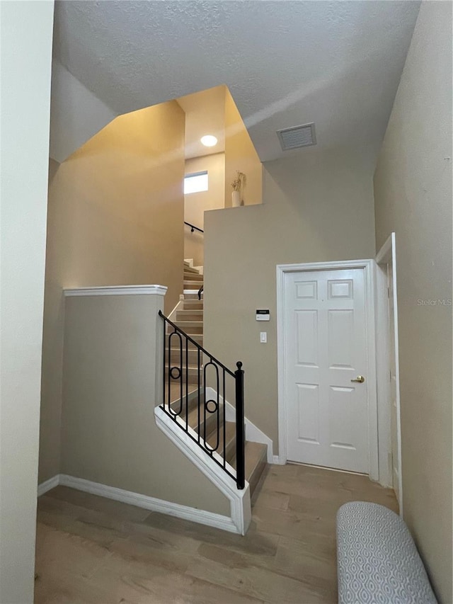 stairway with hardwood / wood-style floors and a textured ceiling