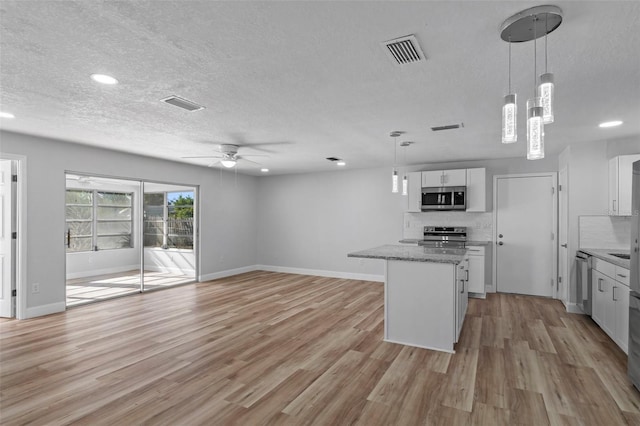 kitchen featuring decorative backsplash, stainless steel appliances, ceiling fan, decorative light fixtures, and white cabinetry