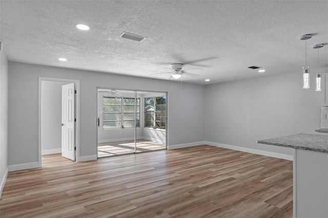 unfurnished living room with ceiling fan, light wood-type flooring, and a textured ceiling