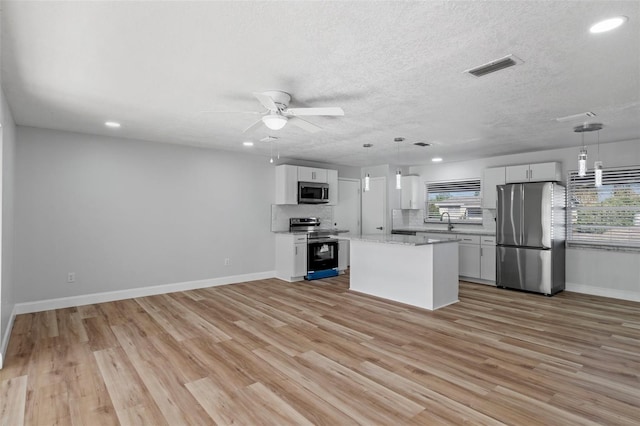 kitchen with white cabinets, a center island, stainless steel appliances, and hanging light fixtures