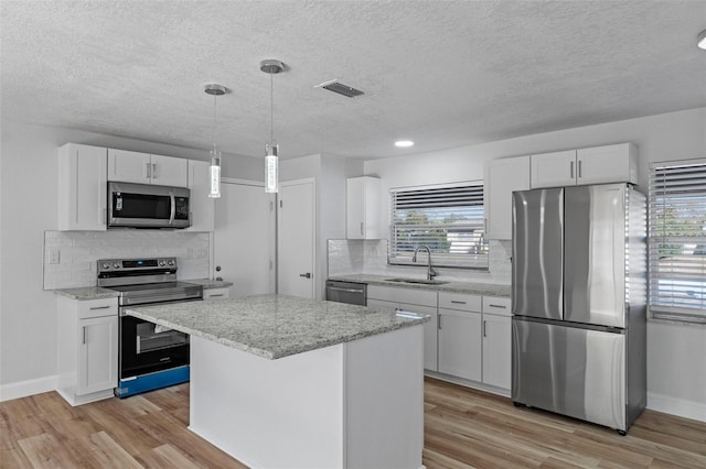 kitchen featuring white cabinets, appliances with stainless steel finishes, a kitchen island, and sink