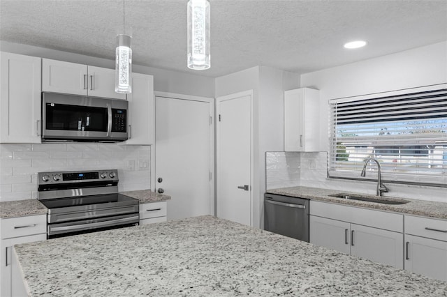 kitchen featuring sink, hanging light fixtures, decorative backsplash, white cabinetry, and stainless steel appliances