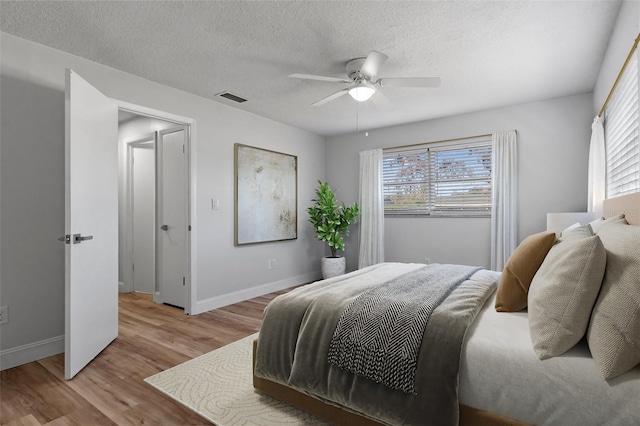 bedroom featuring ceiling fan, light hardwood / wood-style flooring, and a textured ceiling