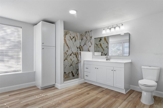 bathroom with hardwood / wood-style flooring, vanity, toilet, and walk in shower