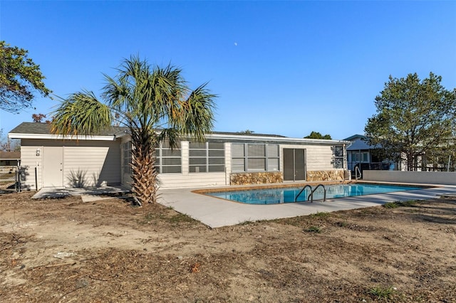 rear view of house featuring a fenced in pool and a storage shed