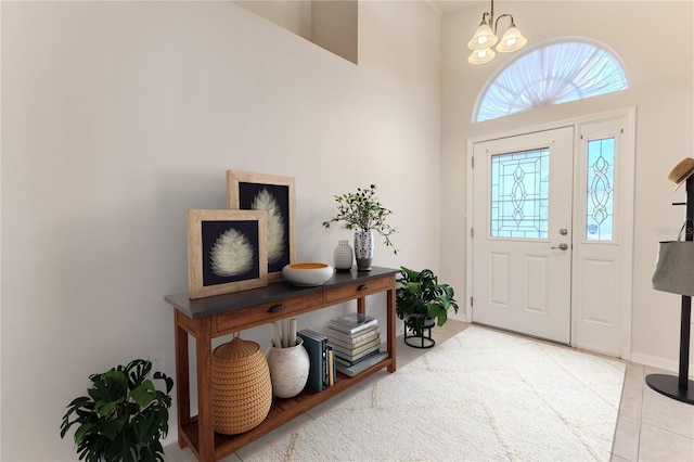 tiled foyer entrance featuring a high ceiling and a notable chandelier