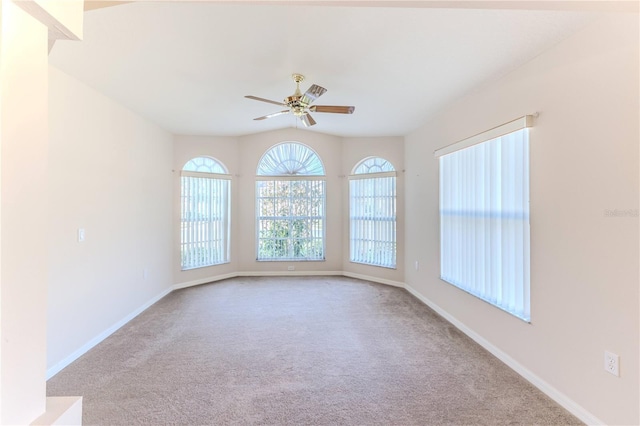 spare room featuring ceiling fan, lofted ceiling, and light carpet