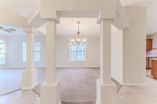 tiled empty room featuring ceiling fan with notable chandelier