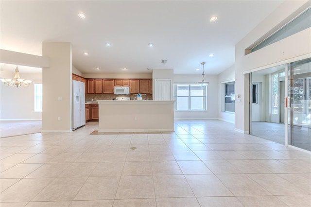 kitchen featuring pendant lighting, a center island, white appliances, light tile patterned floors, and a notable chandelier