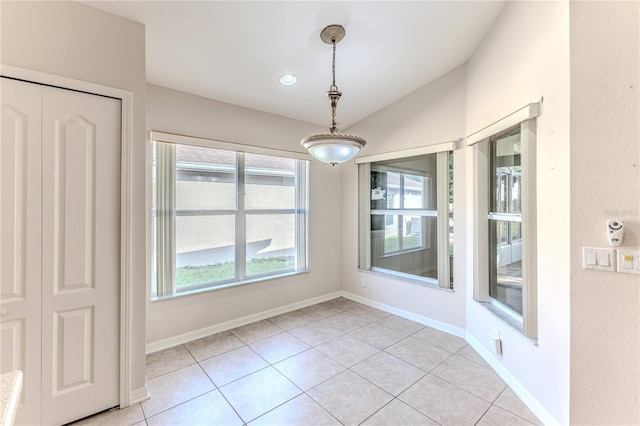 unfurnished dining area with light tile patterned floors and vaulted ceiling