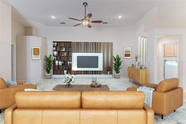 carpeted living room featuring ceiling fan and washer / dryer