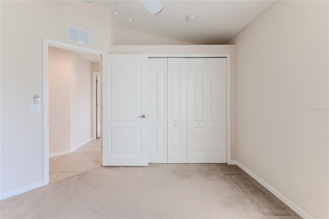 unfurnished bedroom featuring ceiling fan, vaulted ceiling, light carpet, and a closet