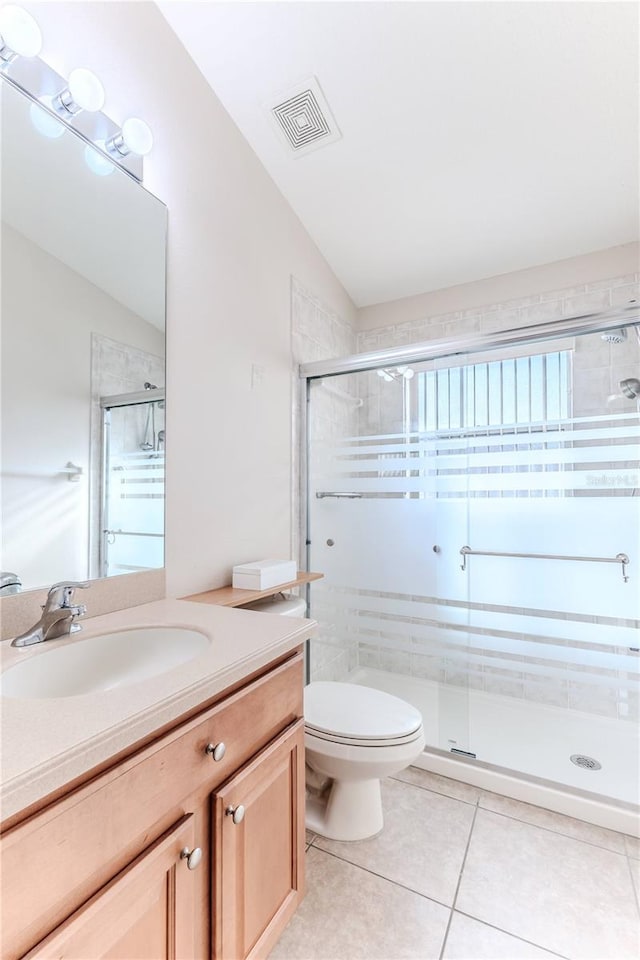 bathroom with tile patterned flooring, vaulted ceiling, toilet, a shower with door, and vanity