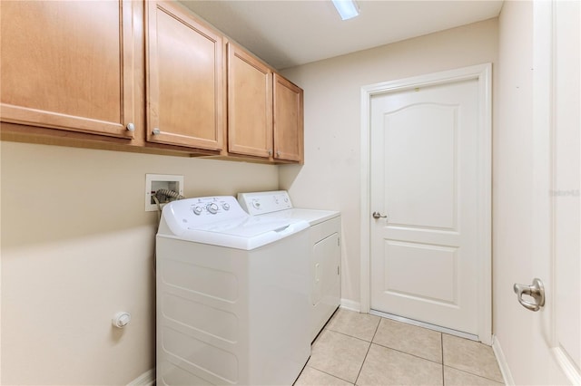 clothes washing area with washing machine and clothes dryer, light tile patterned flooring, and cabinets