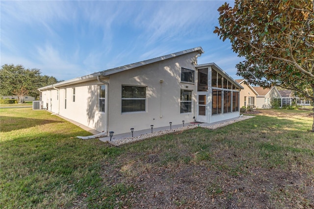 back of property with a lawn, a sunroom, and central AC unit