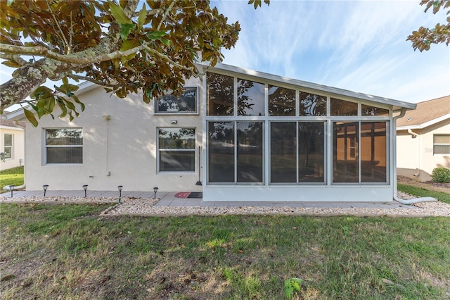 rear view of house featuring a sunroom and a yard