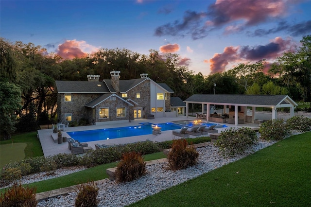 pool at dusk with a gazebo, a jacuzzi, an outdoor hangout area, and a patio