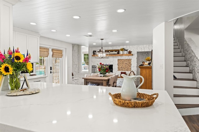 kitchen with light stone countertops, dark hardwood / wood-style flooring, pendant lighting, a fireplace, and white cabinets