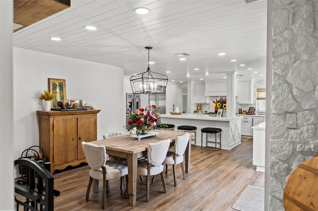 dining area with light wood-type flooring, wood ceiling, and an inviting chandelier