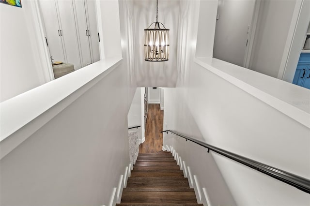 staircase with a chandelier and wood-type flooring