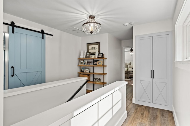 bedroom featuring a barn door, a closet, an inviting chandelier, and light hardwood / wood-style flooring