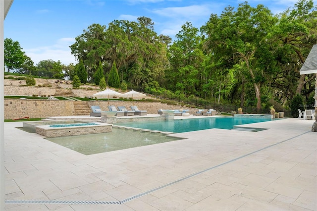 view of swimming pool featuring an in ground hot tub, pool water feature, and a patio