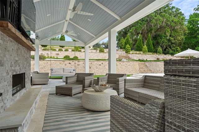 view of patio with an outdoor living space with a fireplace and ceiling fan