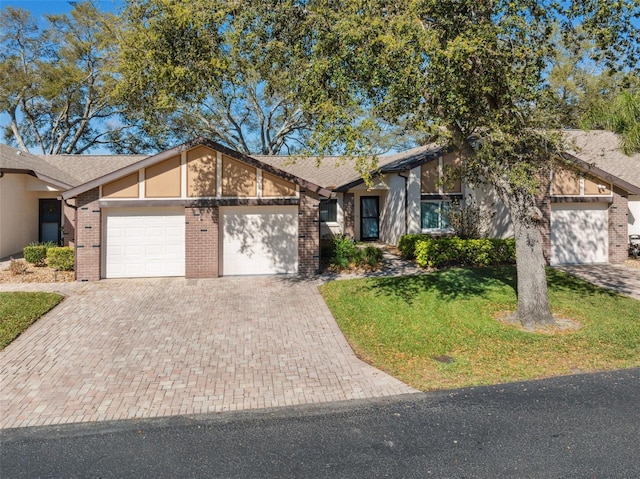 mid-century home featuring decorative driveway, roof with shingles, a front lawn, brick siding, and an attached garage