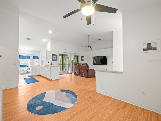 living room with a notable chandelier, light wood-type flooring, lofted ceiling, and sink