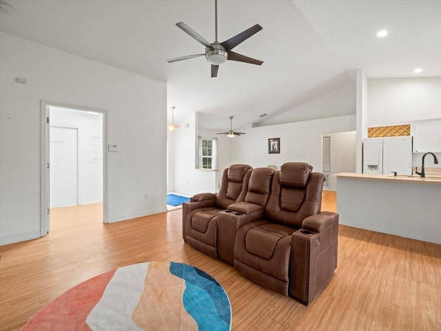 living room featuring ceiling fan, light wood-type flooring, sink, and vaulted ceiling