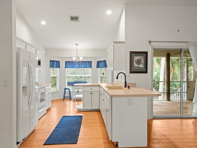 kitchen with stove, sink, white refrigerator with ice dispenser, white cabinetry, and hanging light fixtures