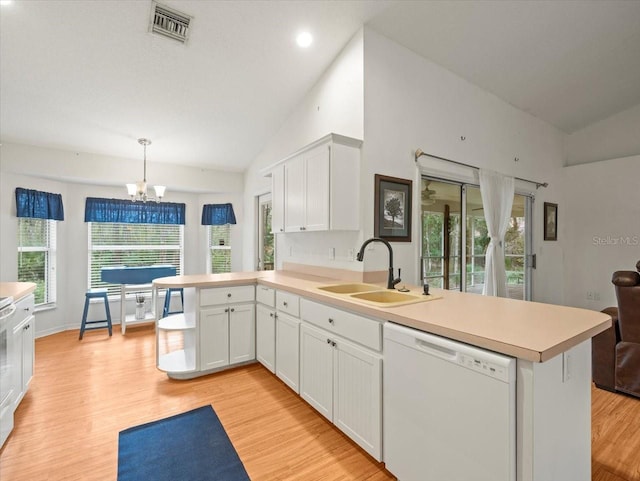 kitchen with sink, kitchen peninsula, white dishwasher, pendant lighting, and lofted ceiling