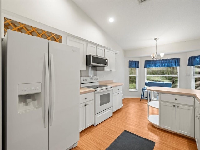 kitchen with lofted ceiling, white cabinetry, hanging light fixtures, and white appliances