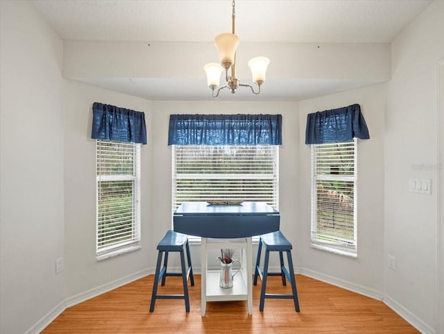 dining area with wood-type flooring and an inviting chandelier