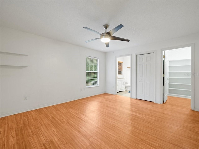 unfurnished bedroom with a textured ceiling, connected bathroom, light hardwood / wood-style floors, and ceiling fan