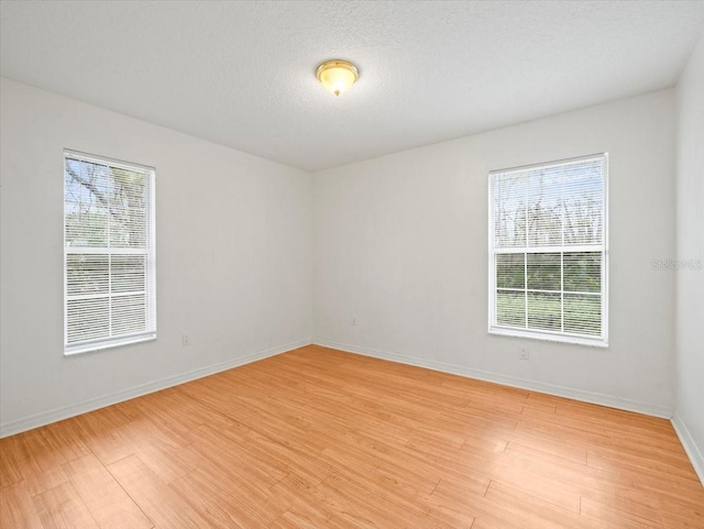 spare room featuring a textured ceiling and light wood-type flooring