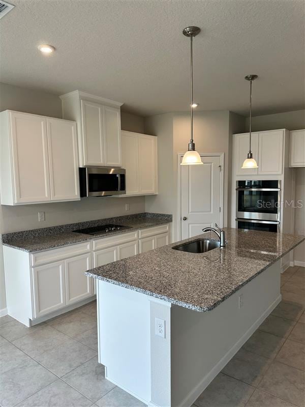 kitchen featuring pendant lighting, sink, a textured ceiling, stainless steel appliances, and white cabinets