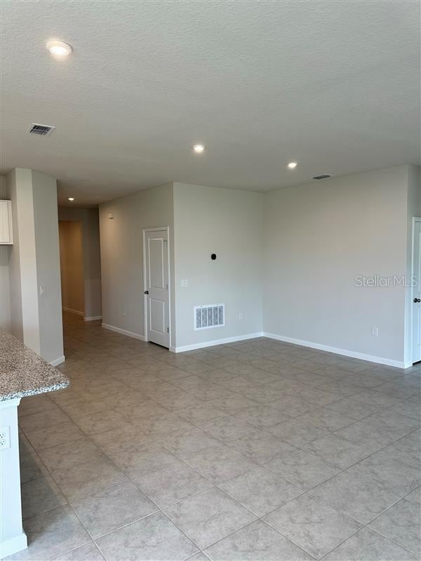 tiled empty room featuring a textured ceiling