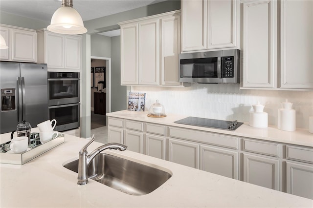 kitchen with backsplash, sink, hanging light fixtures, white cabinetry, and stainless steel appliances