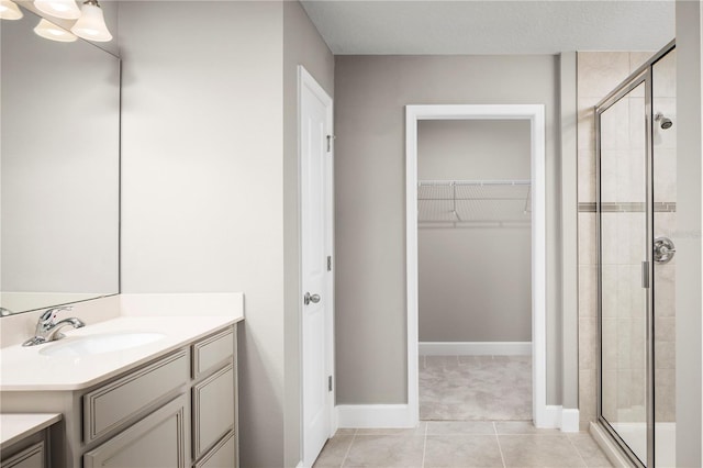 bathroom featuring tile patterned flooring, vanity, and walk in shower