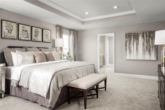 bedroom featuring a tray ceiling, connected bathroom, light colored carpet, and ornamental molding