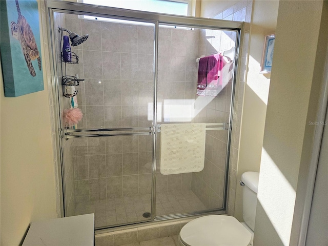 bathroom featuring a shower with shower door and toilet