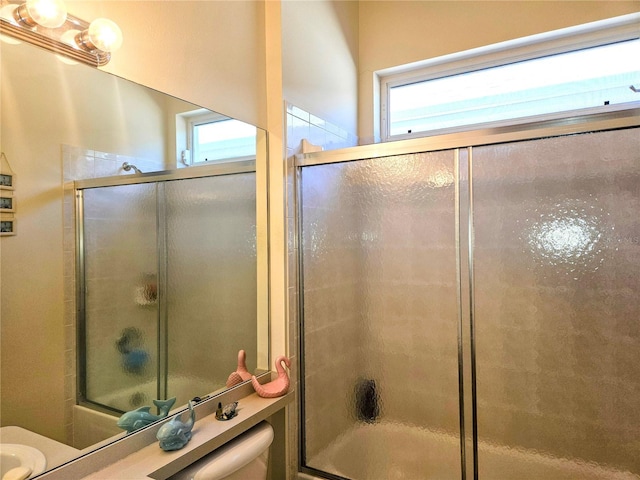 bathroom featuring bath / shower combo with glass door and toilet