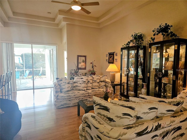 bedroom with access to outside, a tray ceiling, and light wood-type flooring