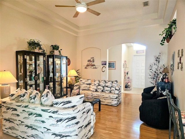 living room with a tray ceiling, ceiling fan, and light hardwood / wood-style floors