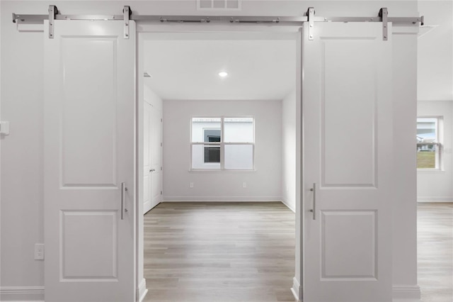 hallway with a barn door and light wood-type flooring