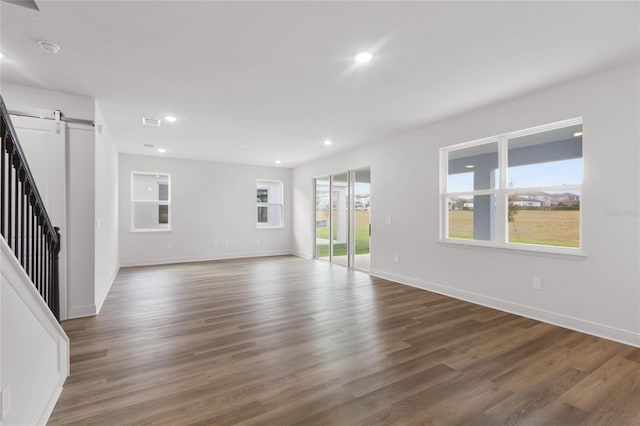 spare room featuring a barn door and dark wood-type flooring